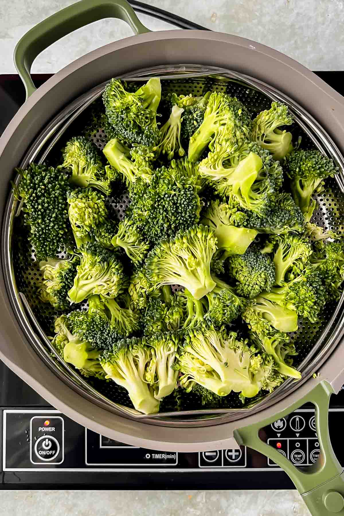 broccoli added to steamer basket of our place pan.
