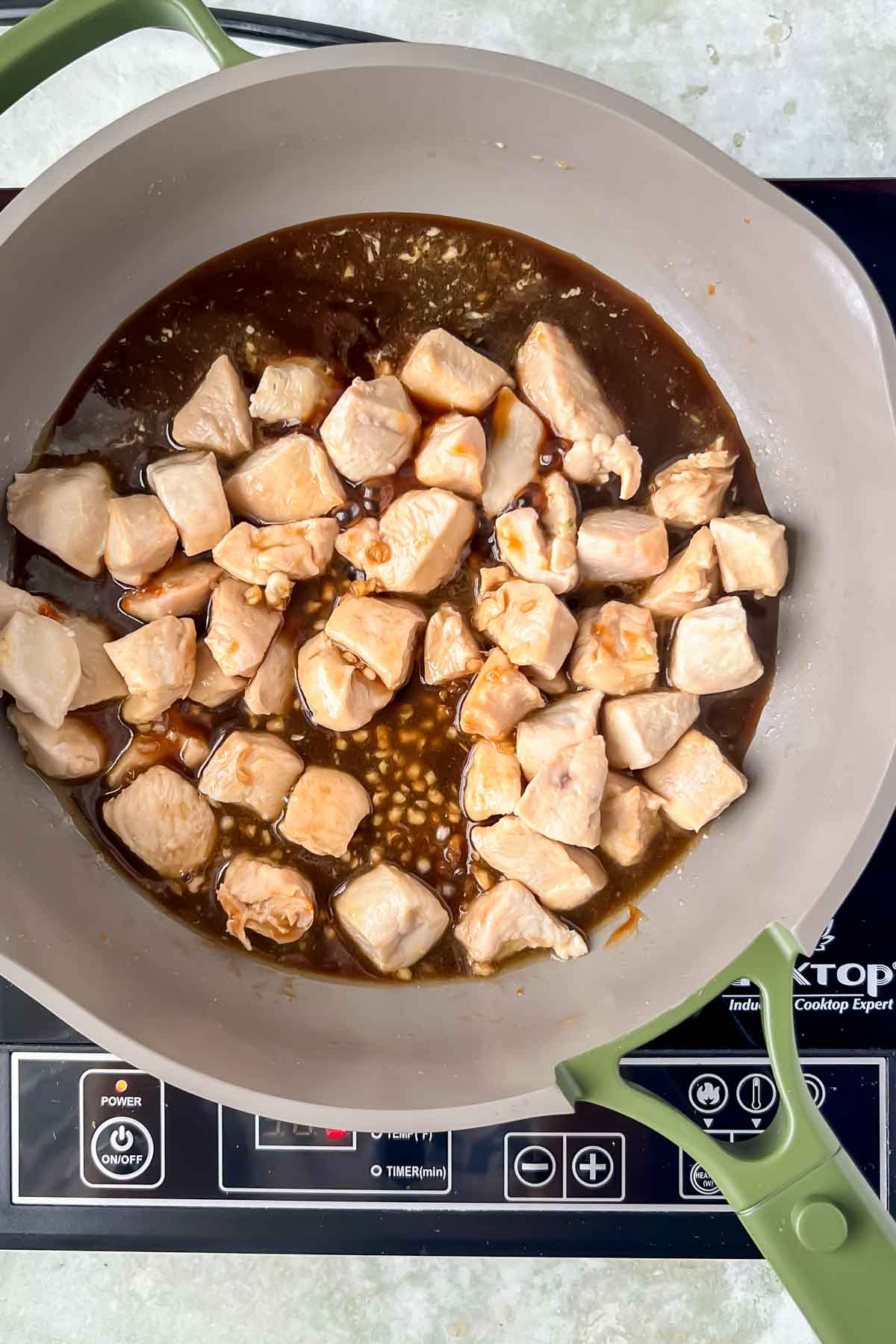 teriyaki sauce added to pan with cooked cubes of chicken.