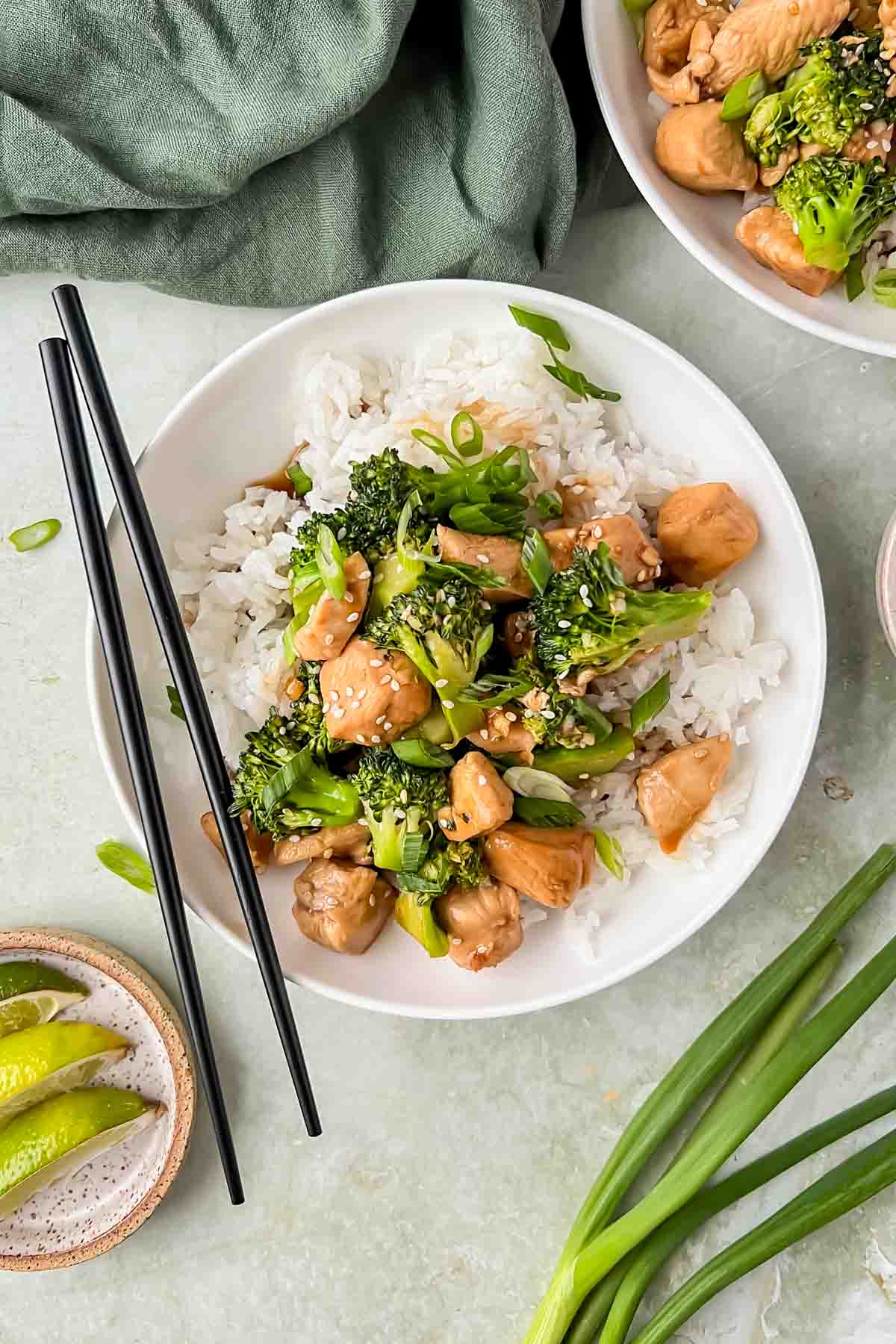 teriyaki chicken and broccoli served over white rice in white bowl with chop sticks.