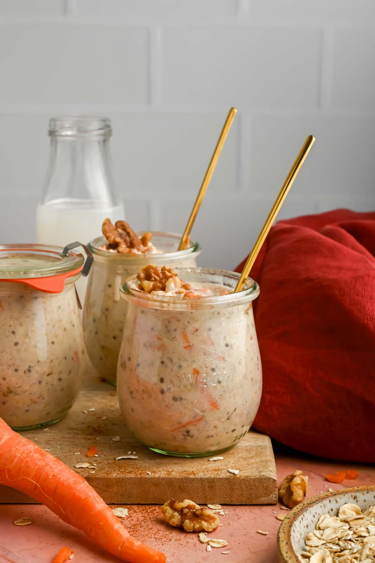 three jars filled with carrot cake overnight oats with gold spoons inserted in jars.