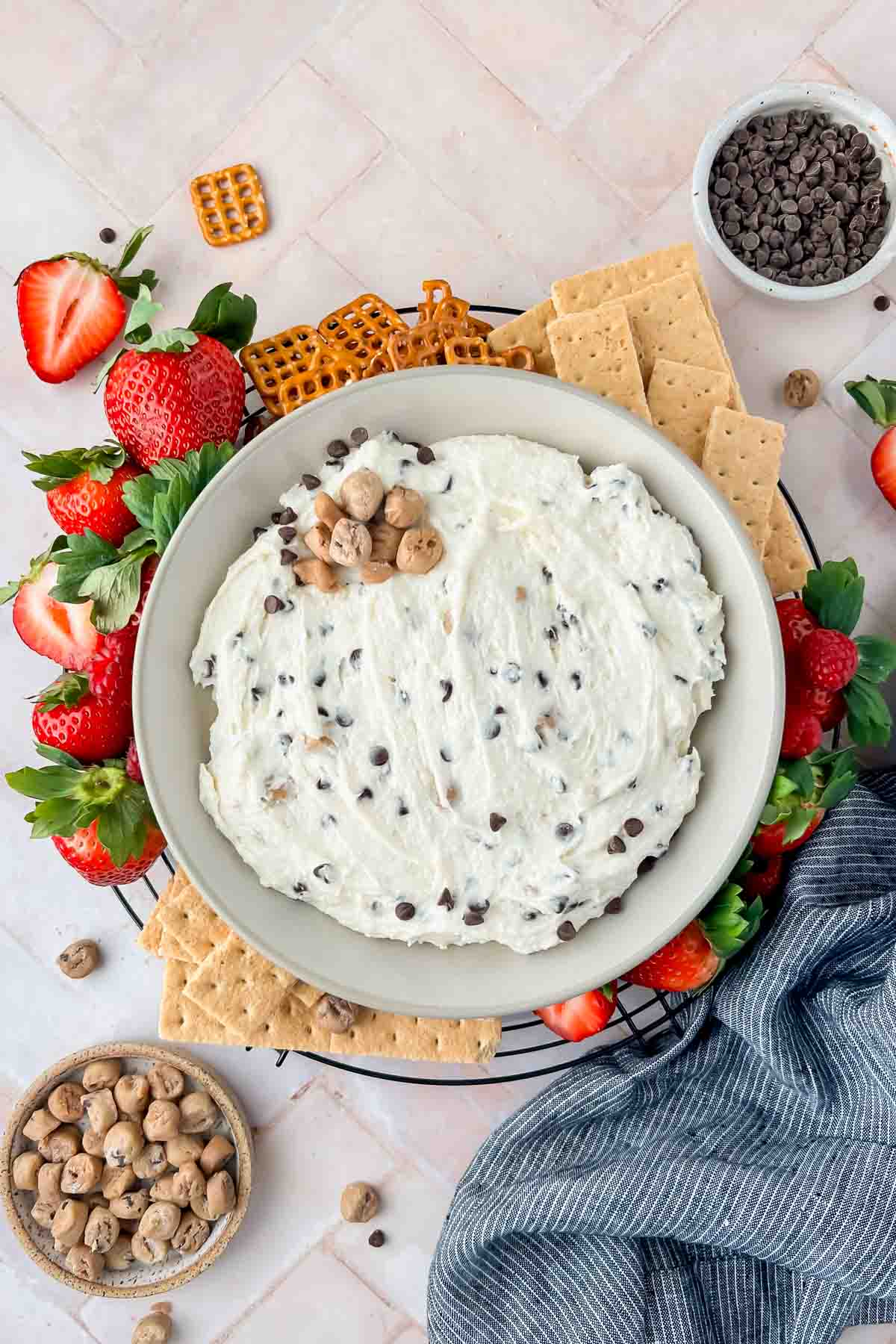 cottage cheese cookie dough dip in gray serving bowl surrounded by pretzels, graham crackers, and strawberries.