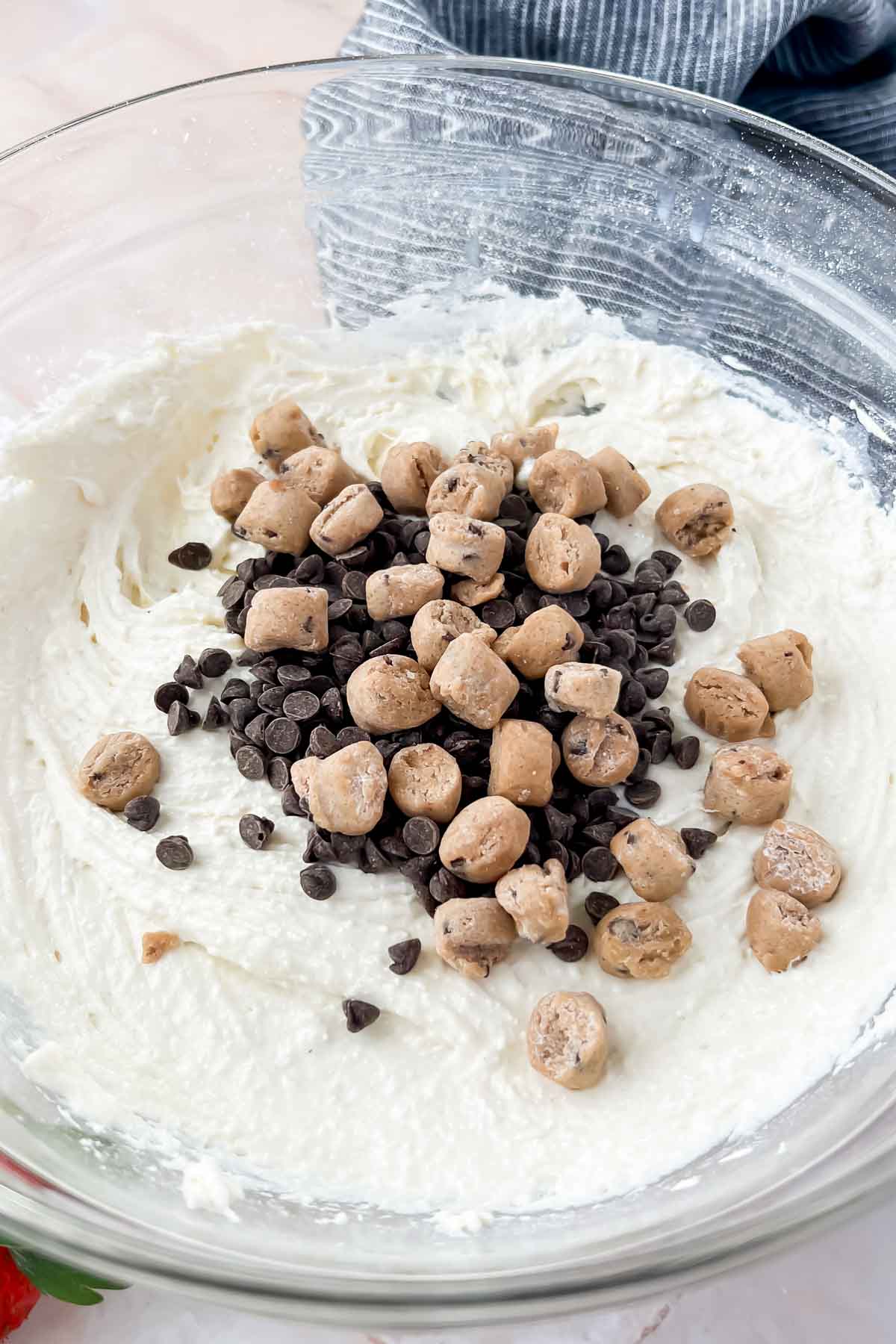 whipped cottage cheese cookie dough dip with mini chocolate chips and cookie dough bites in glass mixing bowl.