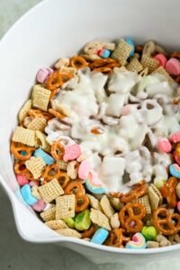 bowl of pretzels, chex cereal, and lucky charms with white chocolate dumped on top.