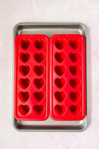 two heart shaped silicone molds on baking sheet.