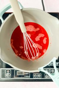 pink jello liquid whisked together in sauce pot.