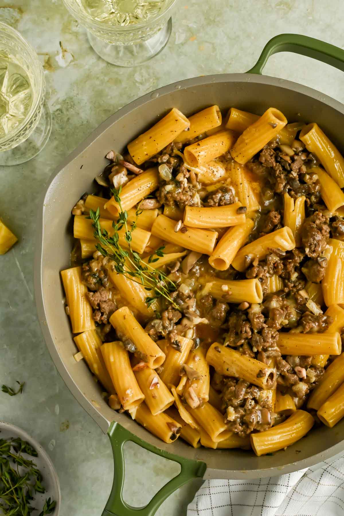 sausage mushroom pasta topped with fresh thyme in gray skillet.