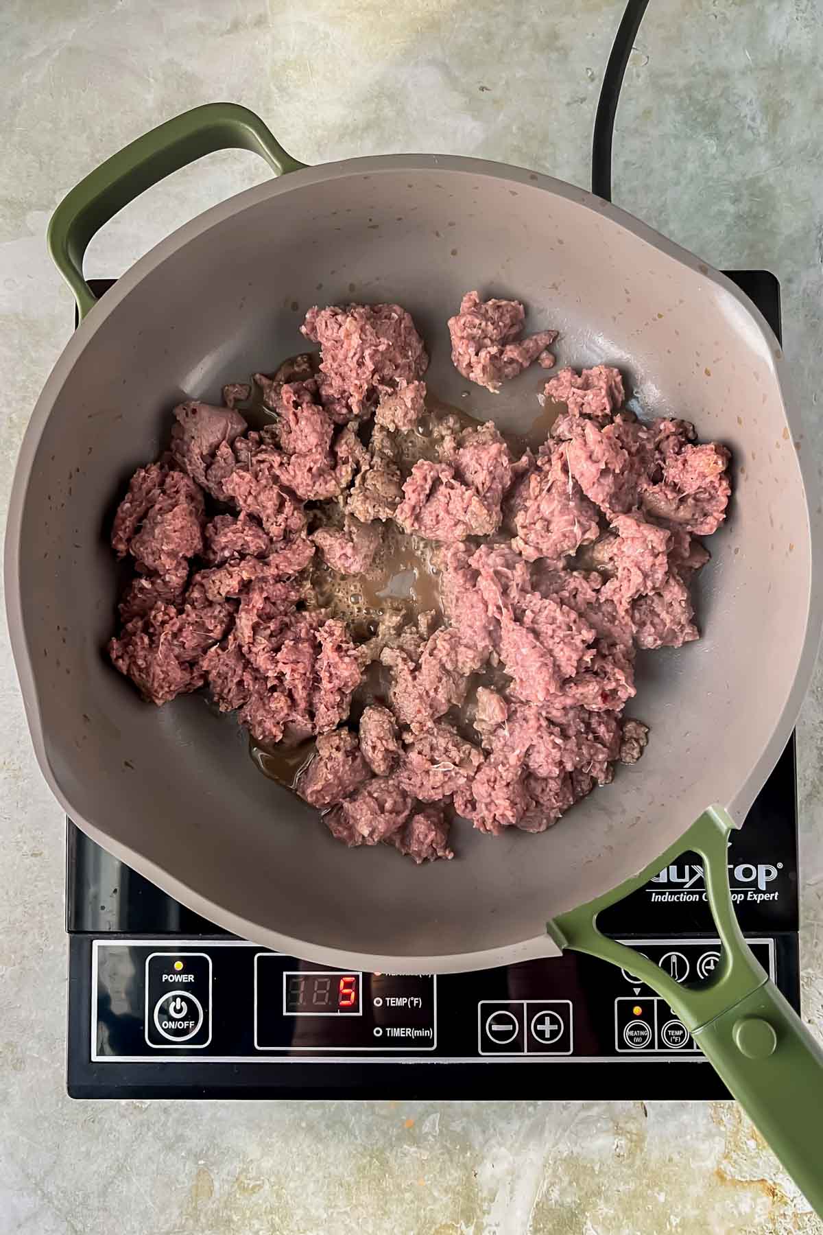 ground sausage cooking in gray skillet.