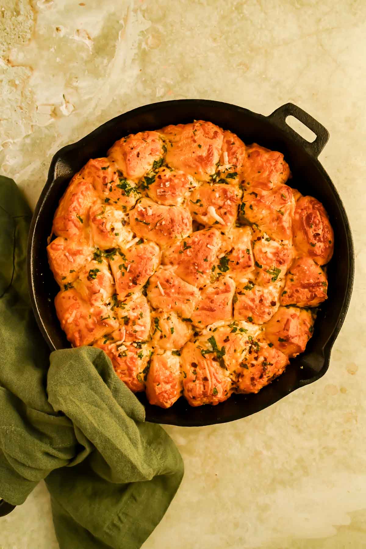cheesy monkey bread garnished with fresh herbs in black skillet.