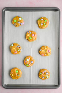 8 cookie dough balls on parchment lined baking sheet.