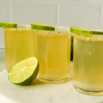 green tea shots topped with lime wedges in sugar rimmed shot glasses on marble platter.