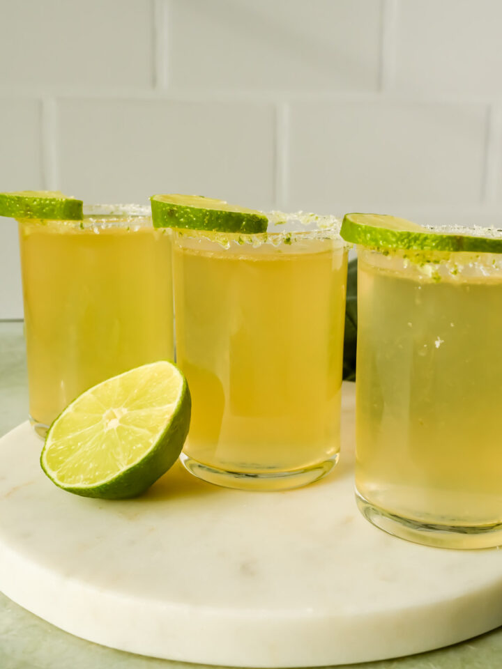 green tea shots topped with lime wedges in sugar rimmed shot glasses on marble platter.