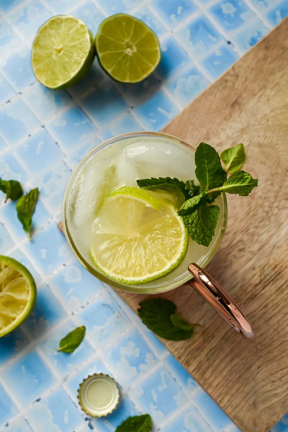 a copper mug filled with tequila mule, lime wedges, and mint sprigs.
