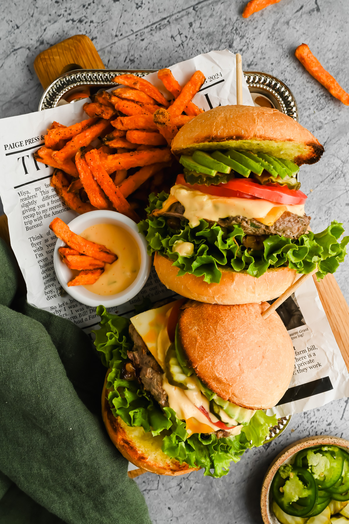 two California burgers laying on a tray served with sweet potato fries and fry sauce.