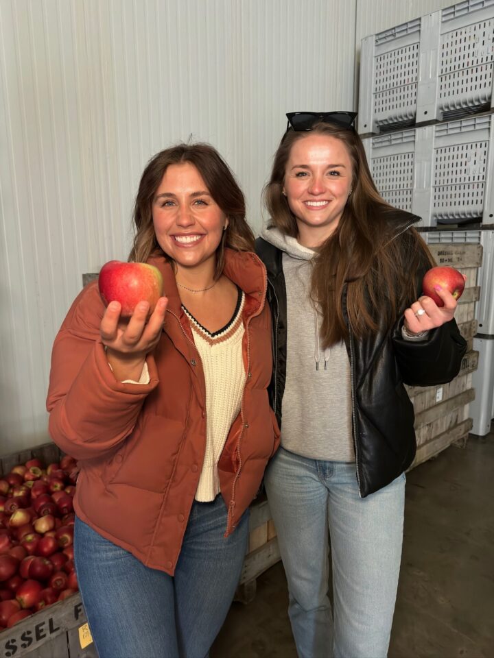 two girls smiling holding an apple in each hand at Dressel Family Farms.
