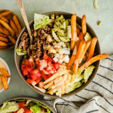 burger bowl loaded with ground beef, cheese, pickles tomatoes and sweet potato fries.