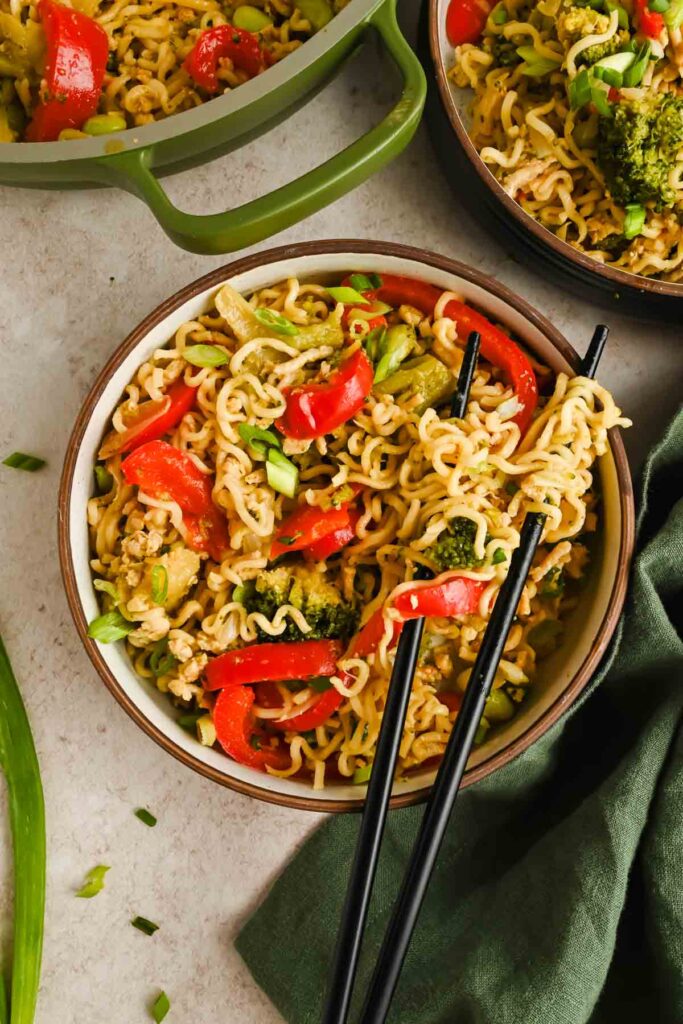 upgraded ramen with peppers, broccoli and edamame in serving bowl with black chopsticks.