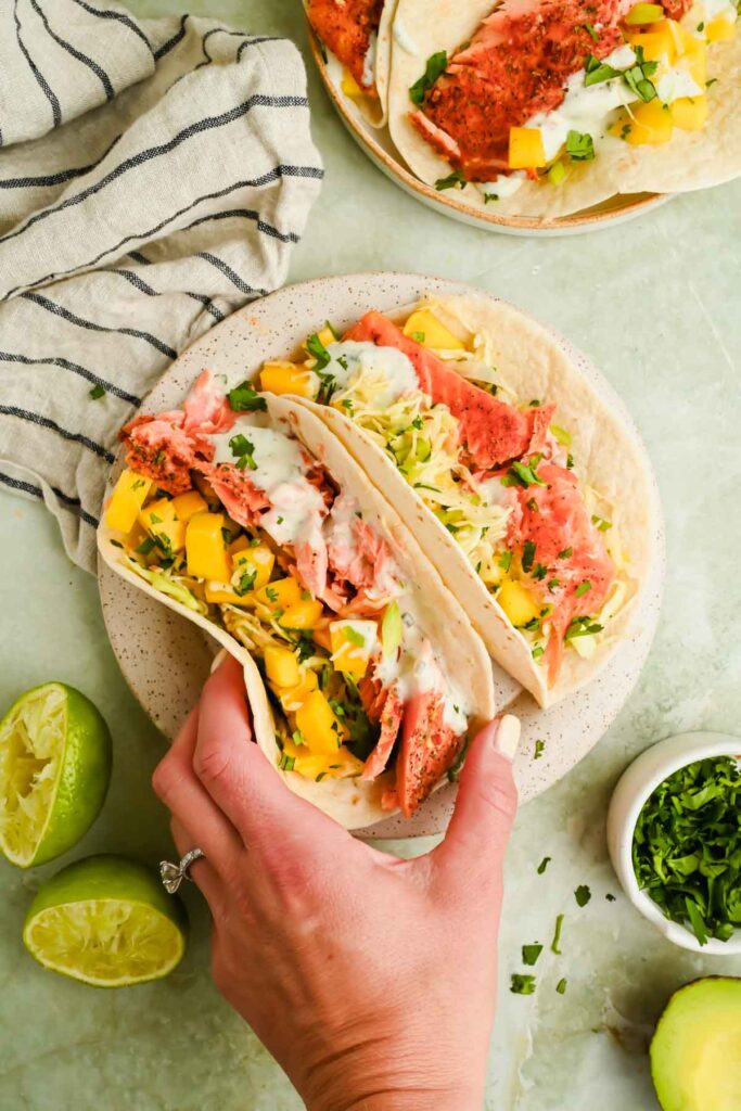 two trout tacos topped with mango slaw served on speckled plate.