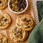 pistachio chocolate chip cookies on parchment lined cooling rack.