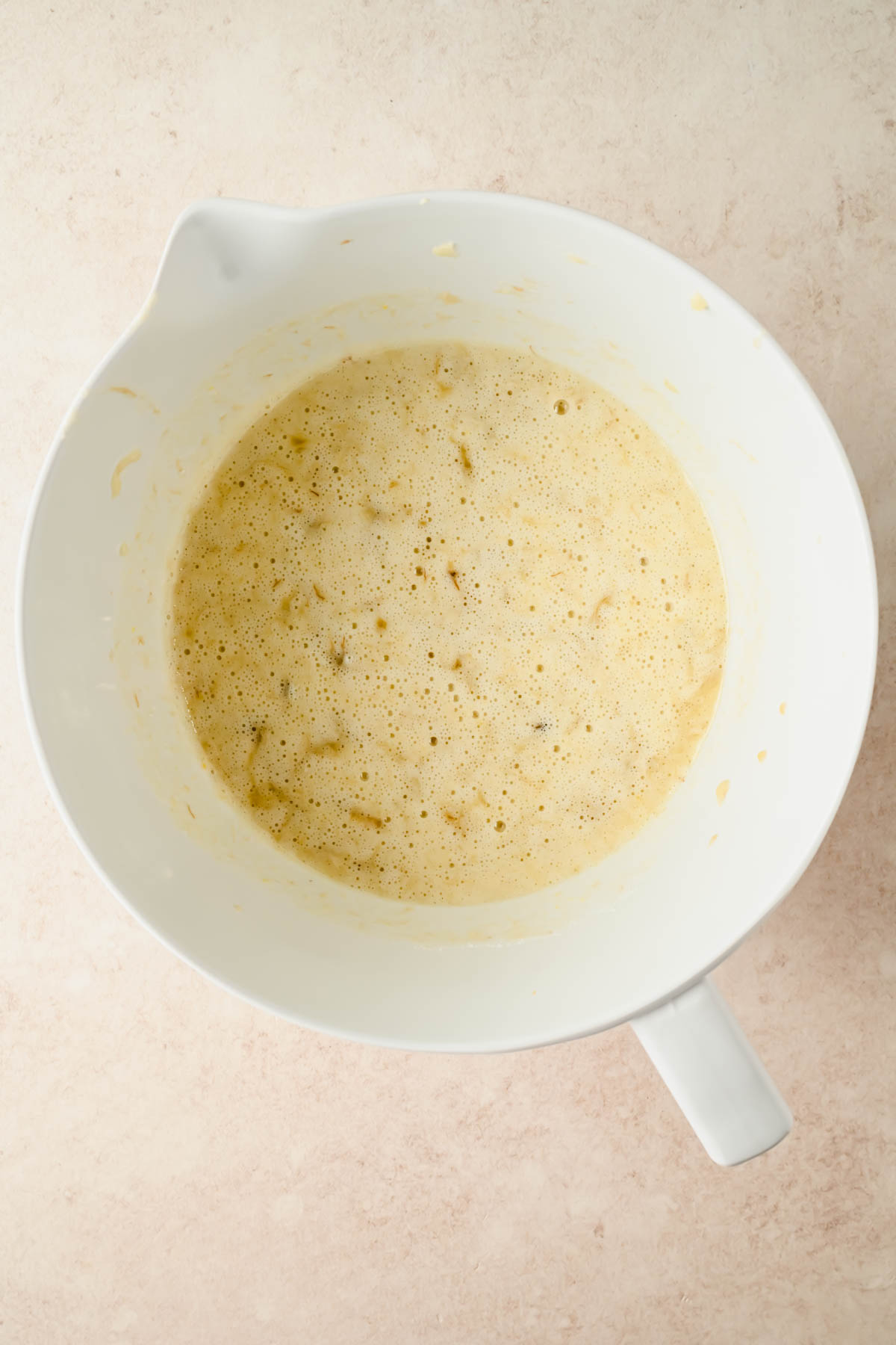 wet ingredients for banana sheet cake mixed in large white mixing bowl.