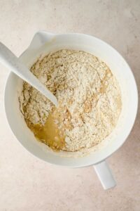 mixing flour into bowl of wet ingredients of banana sheet cake batter.