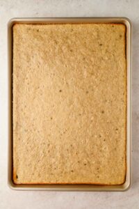 banana sheet cake baked in large silver sheet pan.