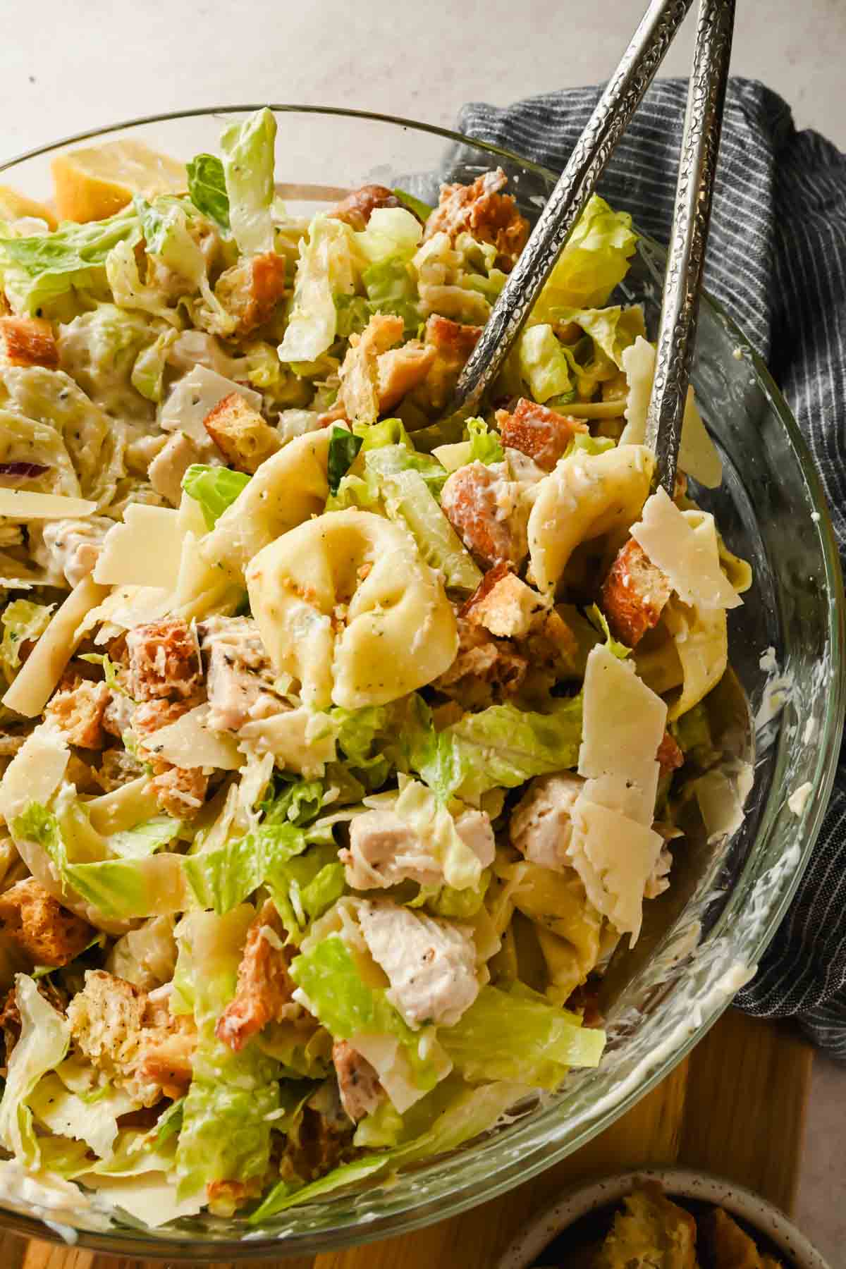 tortellini pasta salad with caesar dressing tossed in glass bowl.