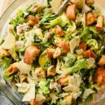 tortellini pasta salad with caesar dressing tossed in glass bowl.