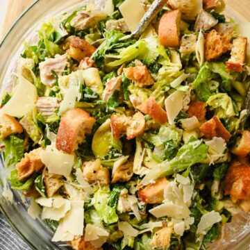 tortellini pasta salad with caesar dressing tossed in glass bowl.