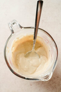 homemade caesar dressing in glass beaker.
