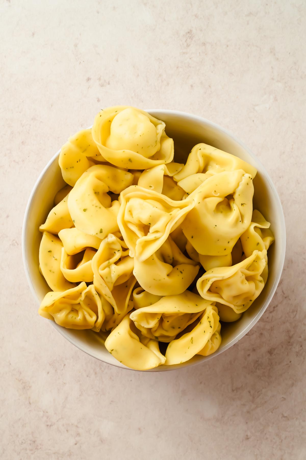cooked tortellini in small white bowl.