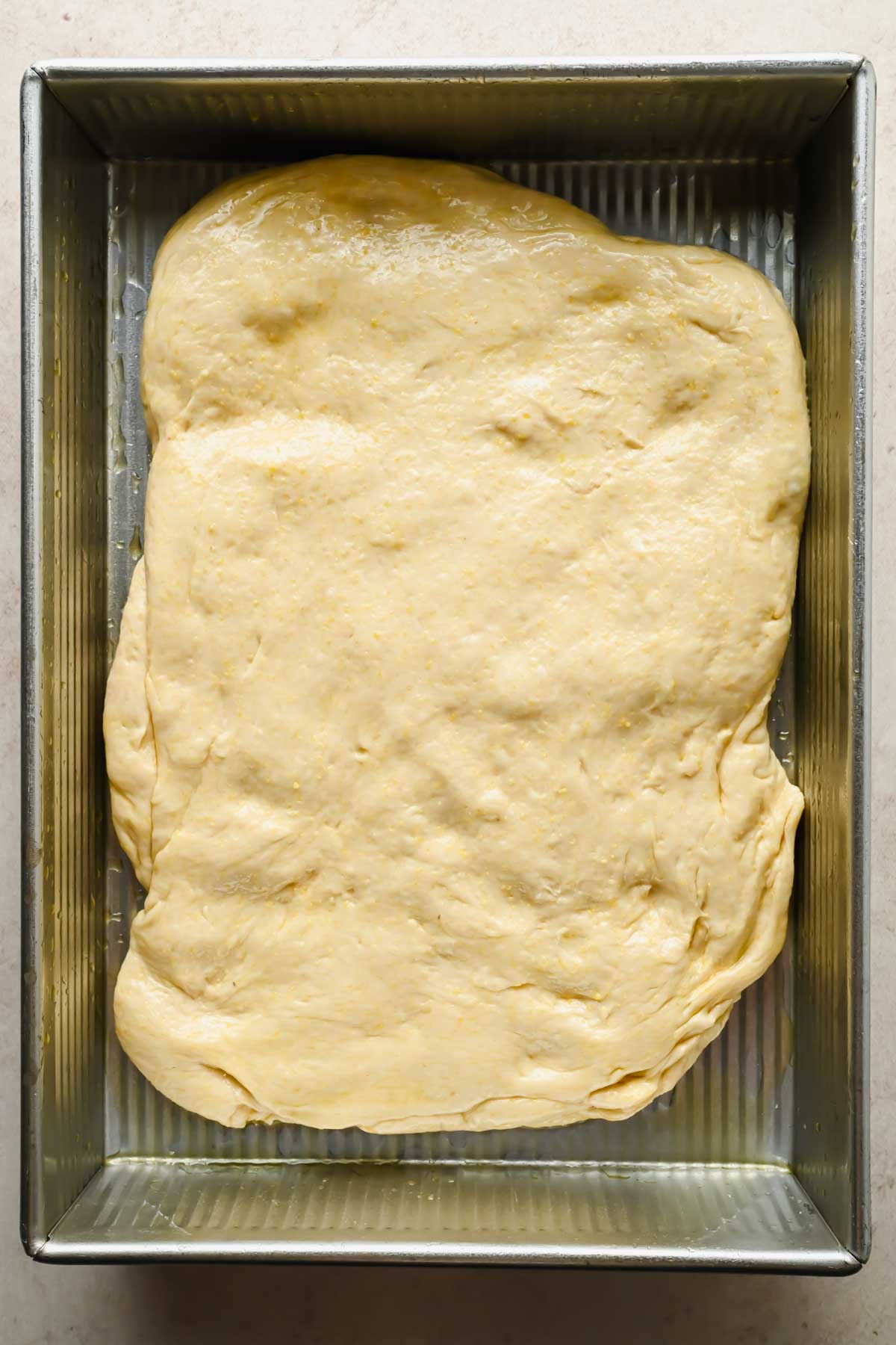 raw focaccia cornbread dough prior to it rising in baking dish before baking.
