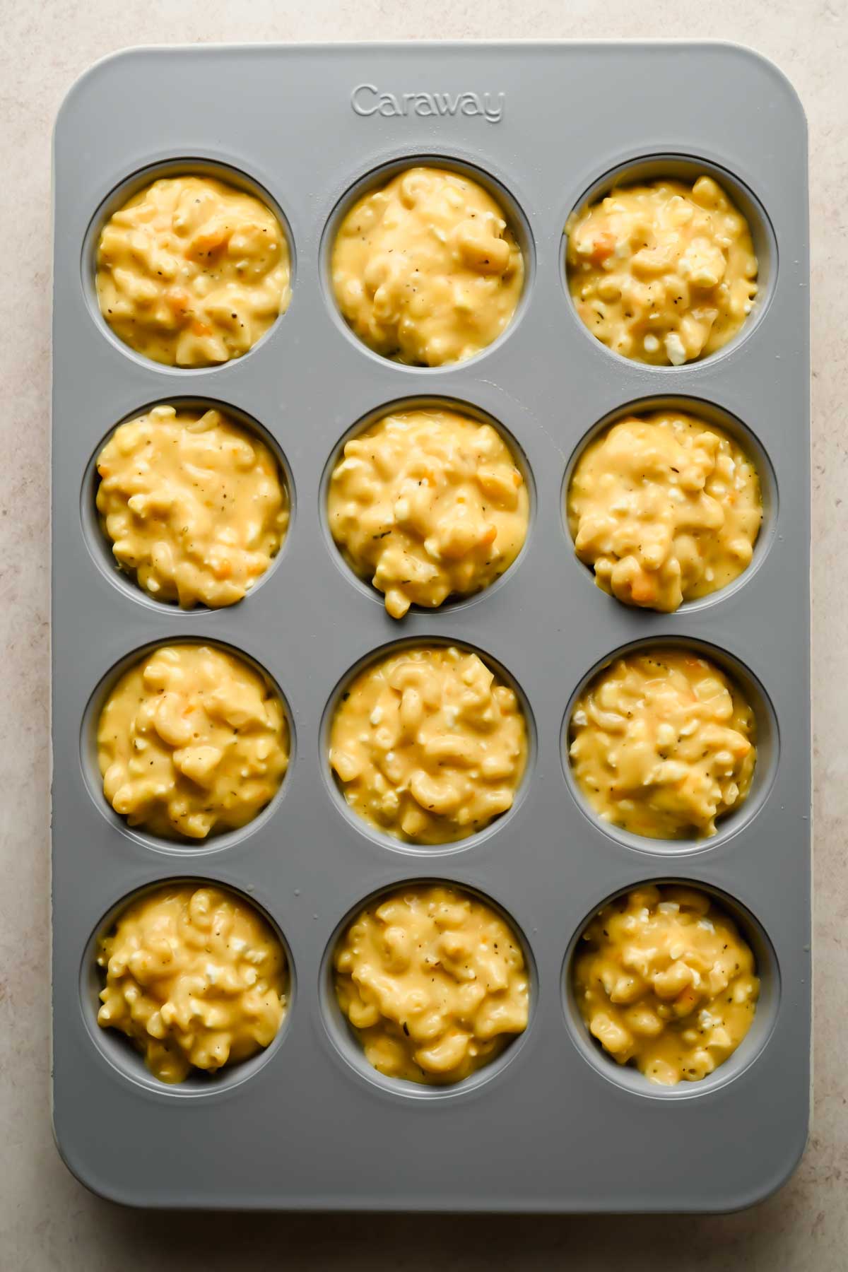 mac and cheese muffin batter in gray muffin tin.