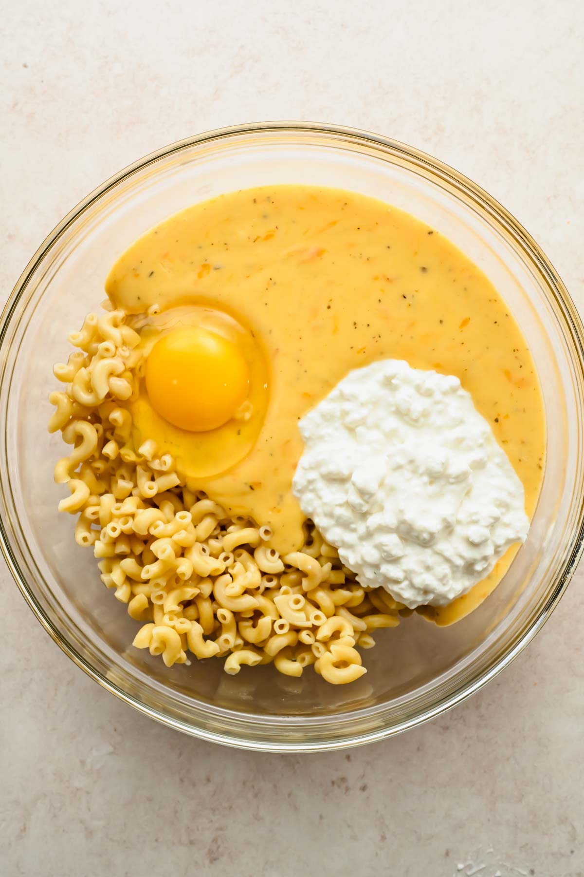 ingredients for mac and cheese muffin in glass mixing bowl.