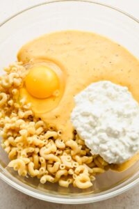 ingredients for mac and cheese muffin in glass mixing bowl.