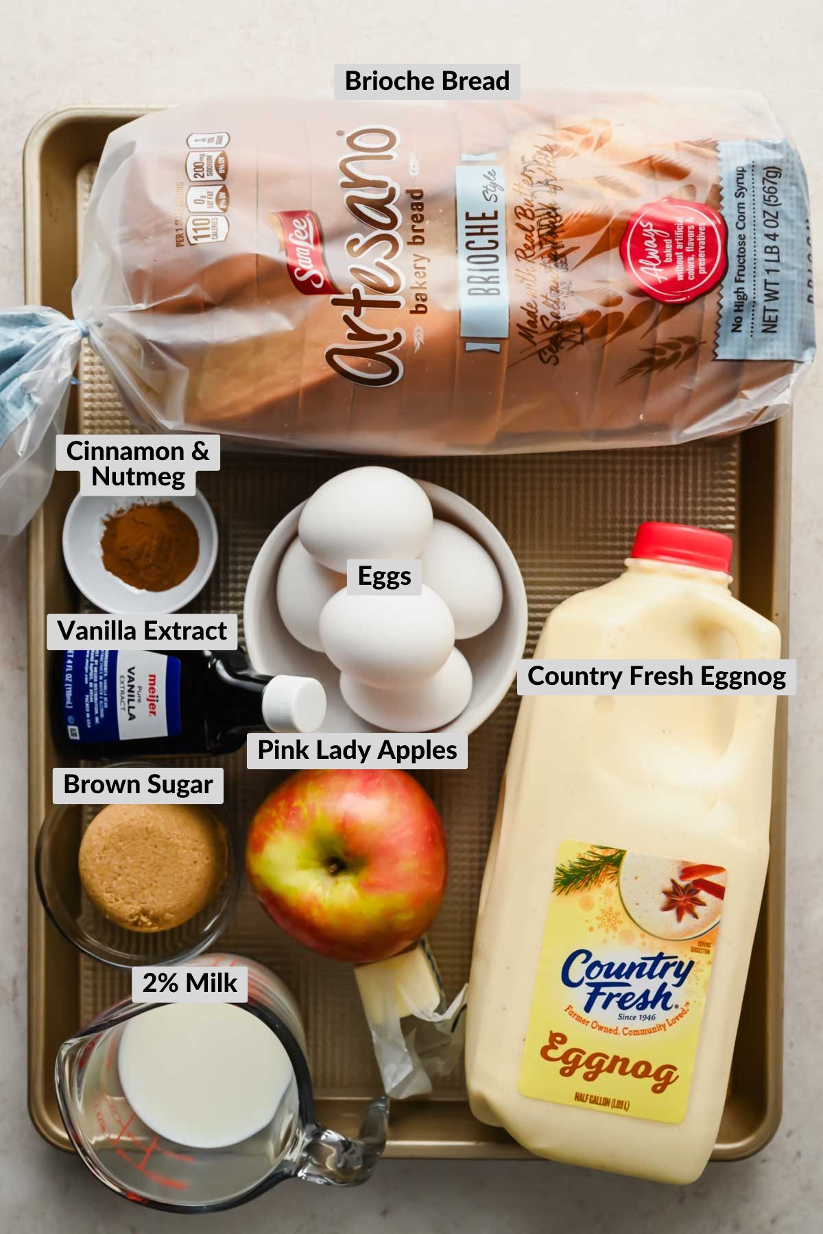 ingredients for eggnog french toast casserole in individual bowls on baking tray.