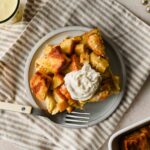 slice of eggnog french toast casserole topped with whipped cream on serving plate with fork.