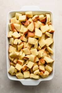 bread cubes stacked in white rectangular baking dish.