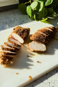 sliced turkey tenderloins on white cutting board.