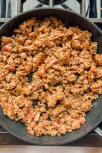 ground Italian Sausage cooking in black skillet.