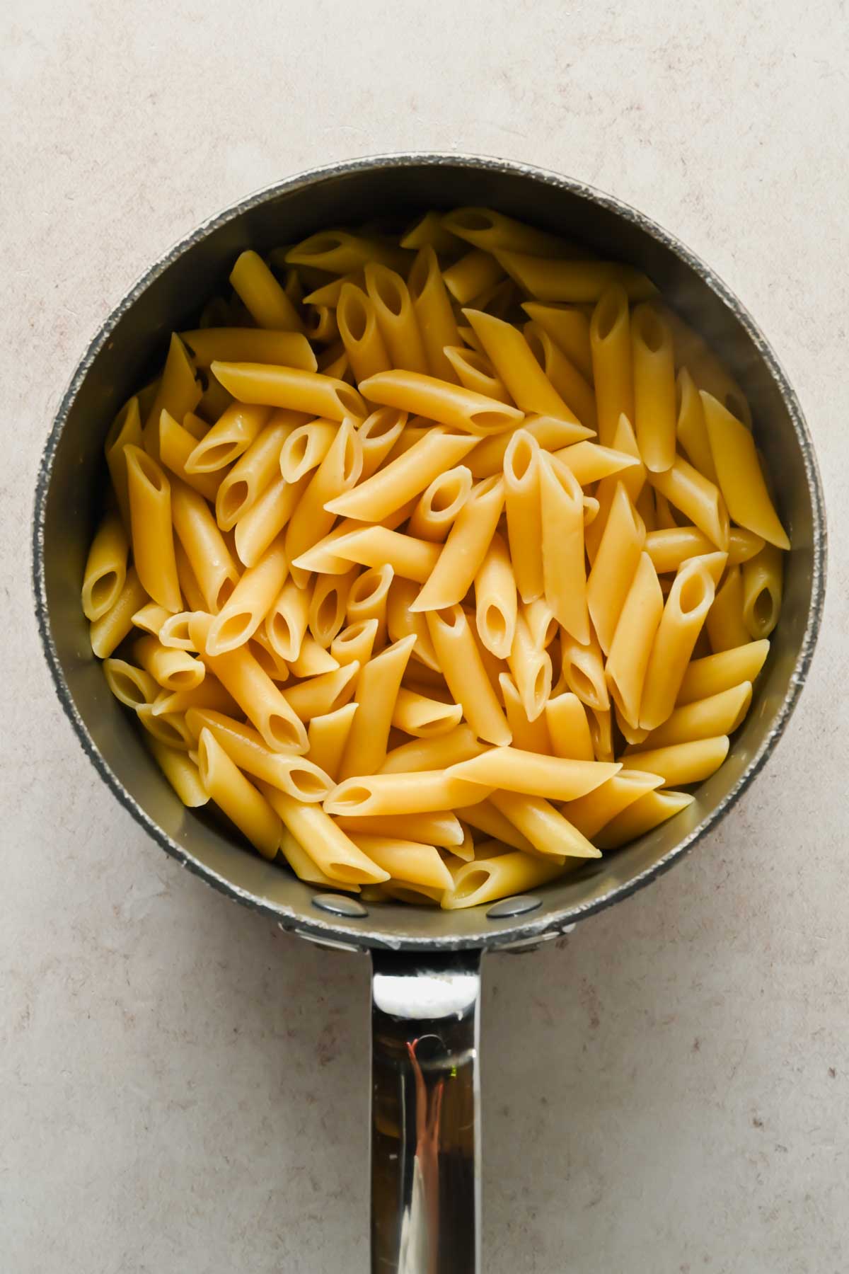cooked penne noodles in sauce pot.