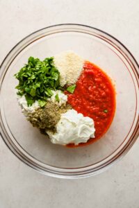 tomato sauce, cottage cheese, parmesan and herbs in glass mixing bowl.