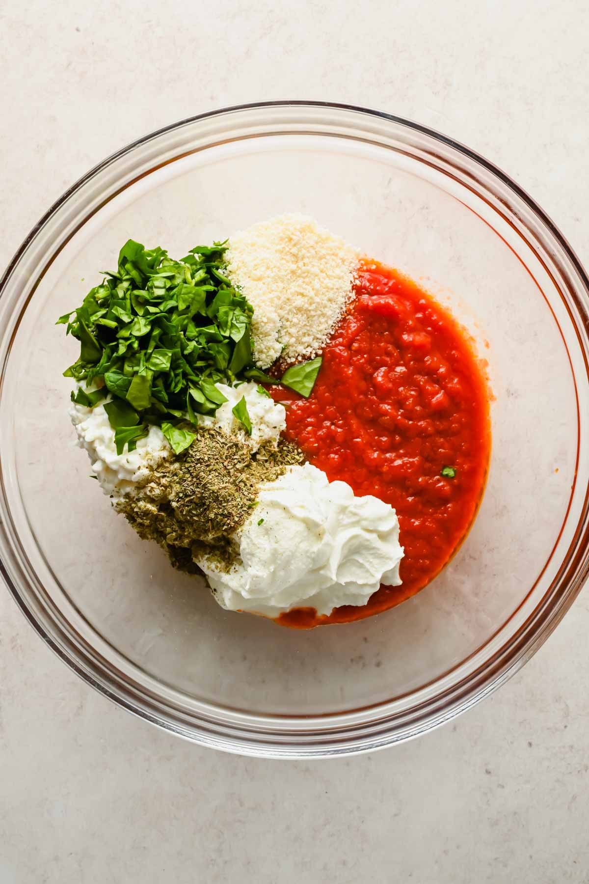 tomato sauce, cottage cheese, parmesan and herbs in glass mixing bowl.