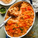 baked buffalo chicken casserole ingredients in large oval baking dish topped with eserving scooped out.