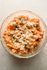 buffalo chicken casserole ingredients mixed together in large glass mixing bowl.