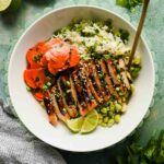 herb rice topped with miso chicken and sliced carrot salad in white serving bowl.