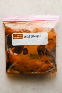 raw chicken marinating in miso sauce in large freezer plastic bag.