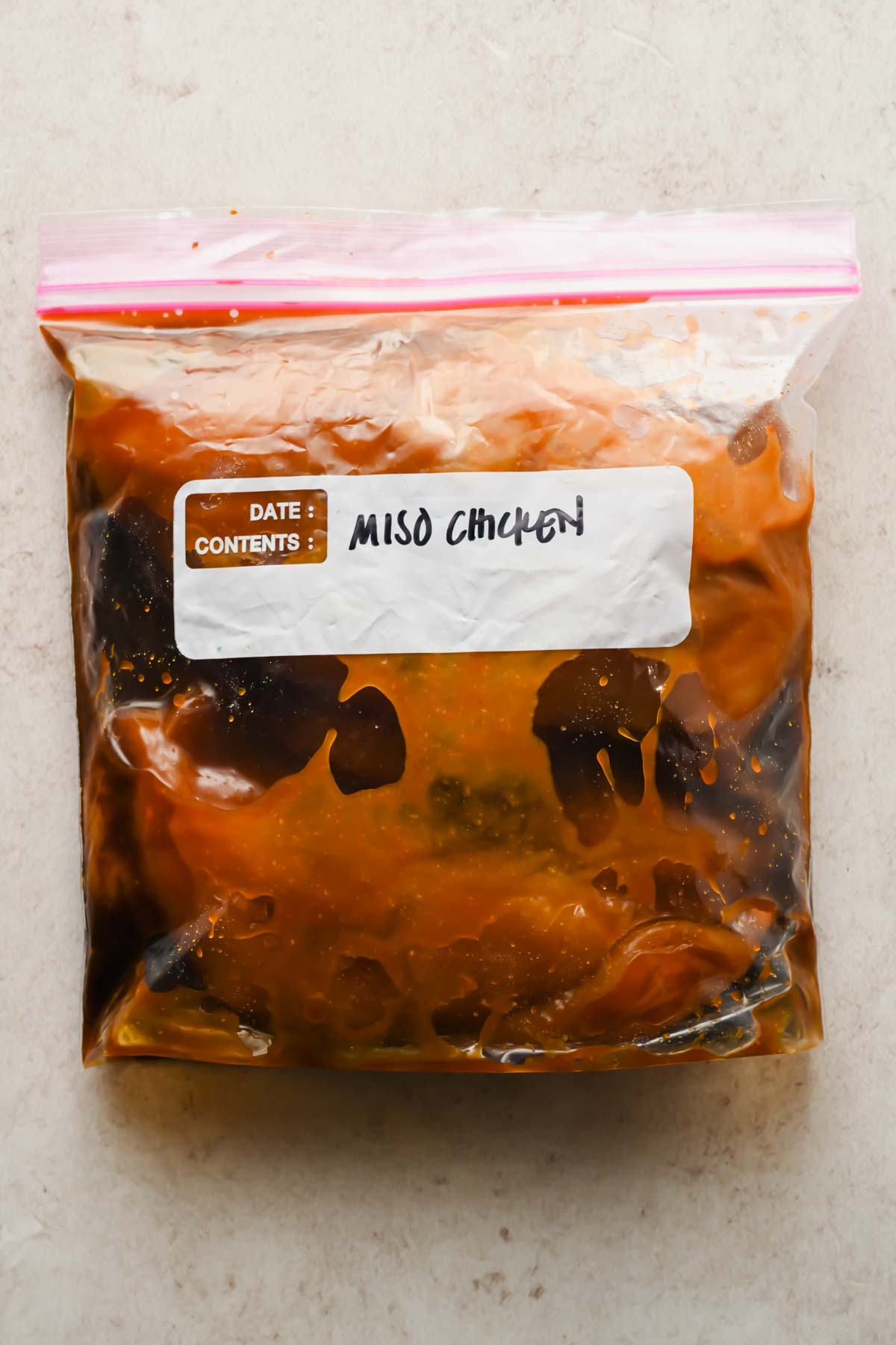 raw chicken marinating in miso sauce in large freezer plastic bag.