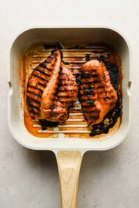 two large chicken breasts cooked on grill pan.