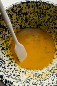 dressing ingredients mixed in speckled mixing bowl.