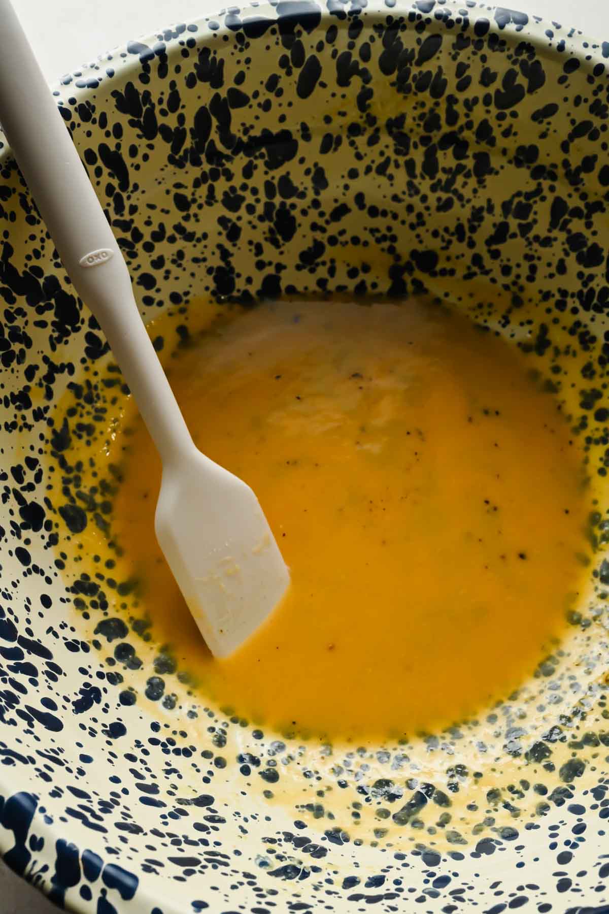 dressing ingredients mixed in speckled mixing bowl.